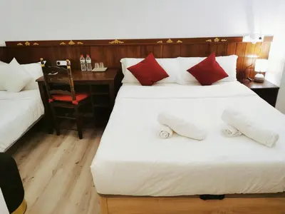 a bedroom with two beds and a desk with a chair at Barcelona CoronaHostal in Badalona