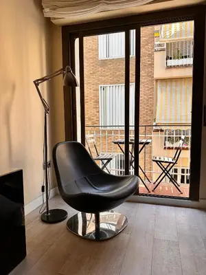 a black chair sitting in a room with a window at Gracia Barcelona Apartment in Barcelona