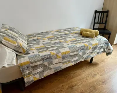 a bed with a quilt on it in a room at Large Apartment near FIRA and City Center in Hospitalet de Llobregat