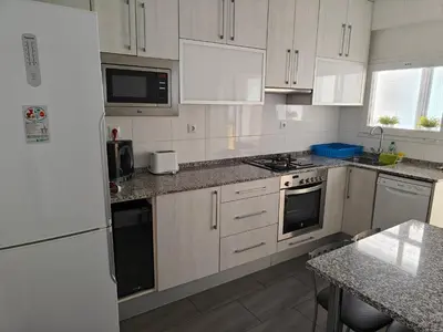 a white kitchen with white appliances and a table at Large Apartment near FIRA and City Center in Hospitalet de Llobregat