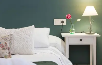 a bed with a table with a vase of flowers on it at LEPANTO APARTMENTS 150m FROM SAGRADA FAMILIA in Barcelona