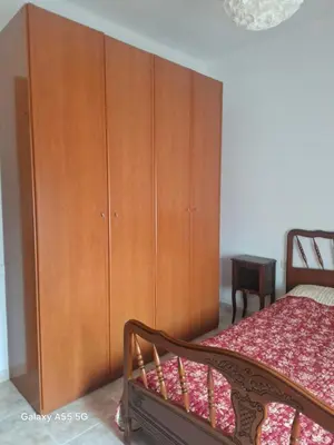 a bedroom with a large wooden cabinet next to a bed at Appartement 6 Personnes - L'arboc in Arbós