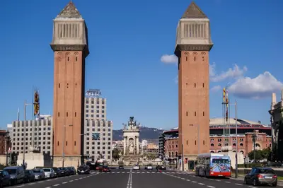 two tall towers in a city with a street at La Fira in Barcelona