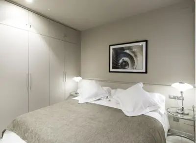 a white bedroom with a bed with white pillows at Glocal Apartments Barcelona in Barcelona