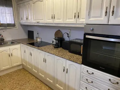a kitchen with white cabinets and a black microwave at Apartamento entero con terraza en el centro de Rubí in Rubí
