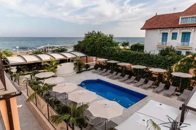 an outdoor patio with tables and umbrellas and the ocean at AB BOUTIQUE HOTEL - Adults only in Sant Vicenç de Montalt