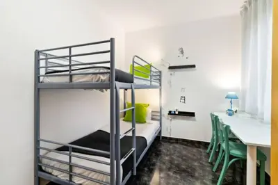 a room with two bunk beds and a table and a desk at Stay U-nique Apartments La Bordeta in Barcelona
