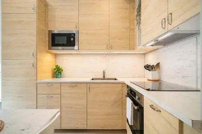 a kitchen with wooden cabinets and a sink and a microwave at NICE CENTRIC APARTMENT in Vilanova i la Geltrú