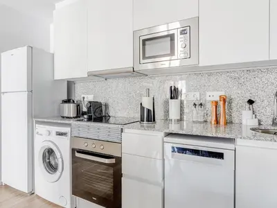 a white kitchen with a microwave and a dishwasher at Limehome Barcelona Carrer de Besalú 90 - estancia temporal in Barcelona