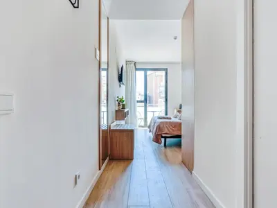 a hallway with a bedroom with a bed and a mirror at Limehome Barcelona Carrer de Besalú 82 in Barcelona