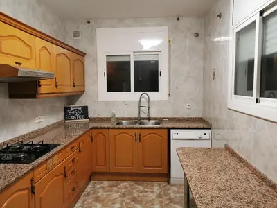 a kitchen with wooden cabinets and a sink at Villa Playa y Montaña in Cunit