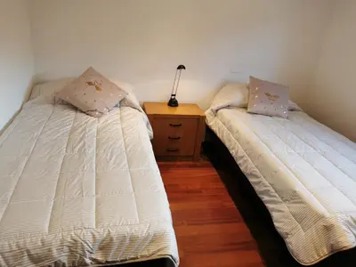 two beds in a room with a dresser and a night stand at Villa Playa y Montaña in Cunit