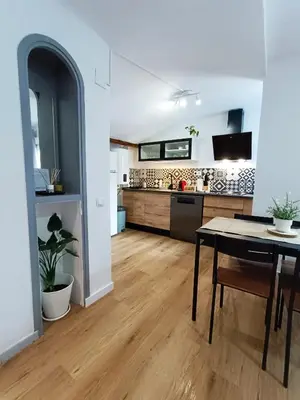a living room with a table and a kitchen at Casa Petits in Manresa