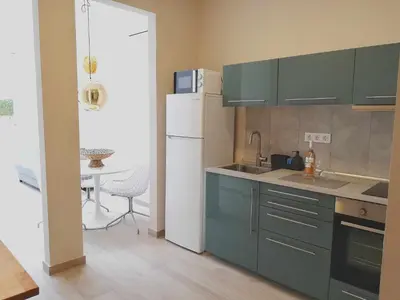 a kitchen with green cabinets and a white refrigerator at Mazi Apartments Chic in Badalona