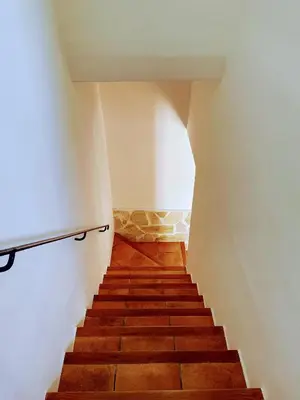 a staircase with wooden floors and a white wall at Masia St Salvador 1582 in Cubelles