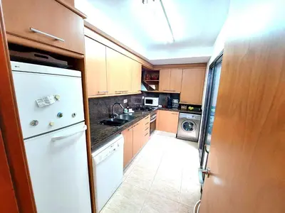 a kitchen with wooden cabinets and a white refrigerator at BRAVAHOLIDAYS-201-Pineda in Pineda de Mar