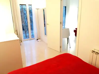 a bedroom with a red bed and a room with windows at Enric Granados 15 in Barcelona