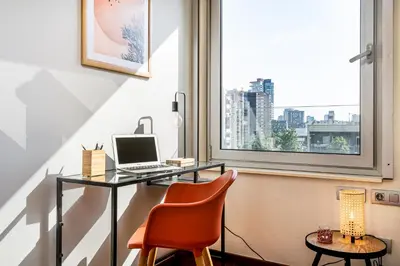a desk with a laptop and a chair in front of a window at Lodging Apartments Forum Llull in Sant Adria de Besos