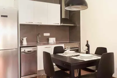 a kitchen with a table with chairs and a refrigerator at Apart céntrico con terraza en Gracia in Barcelona