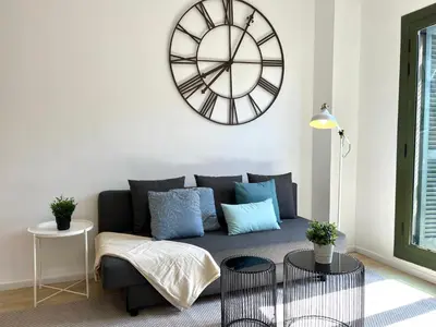 a living room with a couch and a large clock on the wall at Click&Flat Fontanella in Barcelona