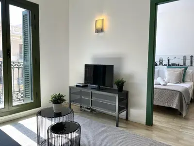a living room with a bed and a tv on a table at Click&Flat Fontanella in Barcelona
