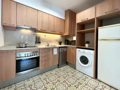 a kitchen with wooden cabinets and a washer and dryer at Click&Flat Fontanella in Barcelona