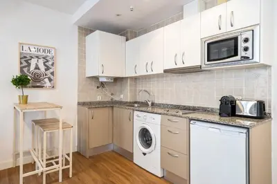 a kitchen with white cabinets and a washer and dryer at Lodging Apartments Liceu G2 in Barcelona