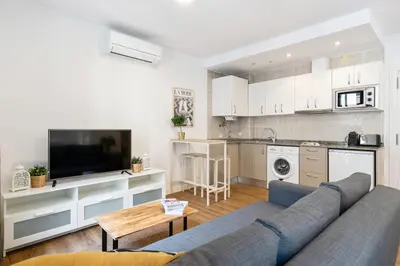 a living room with a blue couch and a kitchen at Lodging Apartments Liceu G2 in Barcelona