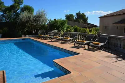 a swimming pool with lounge chairs next to a house at Villa Sitges Ilusión 15 minutes by car from Sitges Sleeps 16 people XXL swimming pool in Olivella