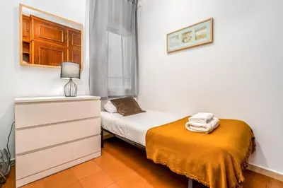 a small bedroom with a bed and a dresser at Arc de Triomf Base 4BR for 5 Lift in Barcelona