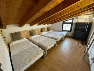 two beds in a room with wooden ceilings at Molí den burch in Santa Eulalia de Ronsaná