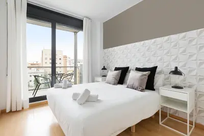 a white bedroom with a large bed and a large window at ChicStays Apartment Vila Olímpica in Barcelona