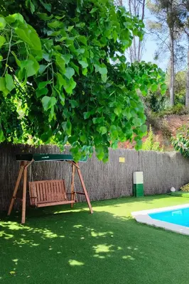 a bench under a tree next to a swimming pool at Casa Can Roura in Vilassar de Dalt