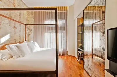 a bedroom with a white bed and a tv at Claris Hotel & Spa GL, a Small Luxury Hotel of the World in Barcelona