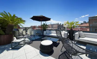 a patio with chairs and tables and an umbrella on a roof at Claris Hotel & Spa GL, a Small Luxury Hotel of the World in Barcelona