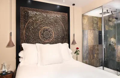 a bedroom with a white bed with a large headboard at Hotel Gran Derby Suites, a Small Luxury Hotel of the World in Barcelona