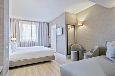 a hotel room with two beds and a chair at Acta CITY47 in Barcelona