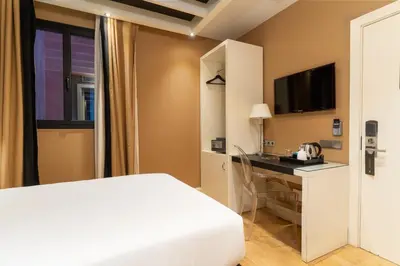 a bedroom with a bed and a desk with a television at U232 Hotel in Barcelona