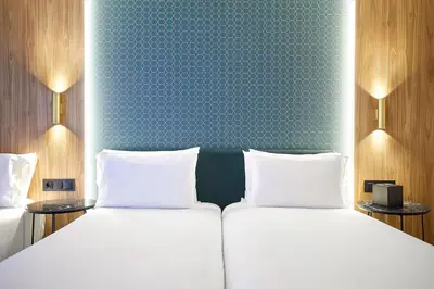 a bedroom with a bed with white sheets and a blue wall at Exe Mitre in Barcelona