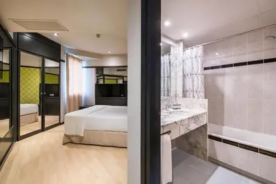 a bedroom with a bed and a bathroom with a tub at Hotel Punt 14 in Gavà