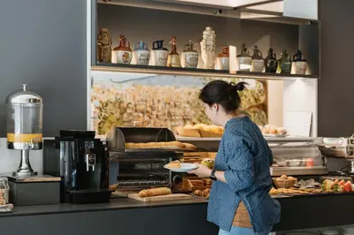 a woman standing in a bakery with a plate of bread at Hotel Travessera in Barcelona