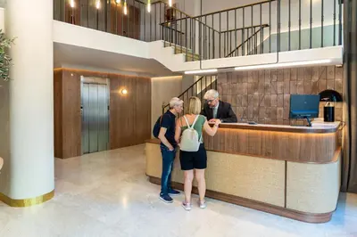 three people standing at a counter in a lobby at Caledonian in Barcelona