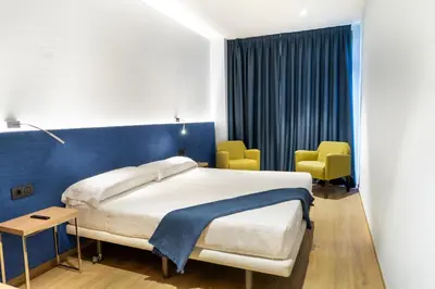 a bedroom with a bed and two yellow chairs at Caledonian in Barcelona