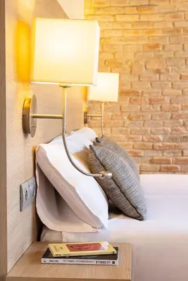 a lamp on a table next to a bed with pillows at Arc La Rambla in Barcelona