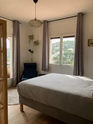 a bedroom with a large bed and two windows at Cozy place, big roof terrace & spectacular views. in Cabrils
