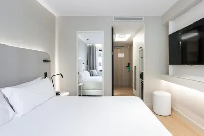 a white bedroom with a white bed and a mirror at Royal Ramblas in Barcelona