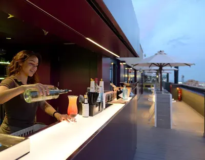 a woman is pouring a drink at a bar at Hotel Barcelona Universal in Barcelona