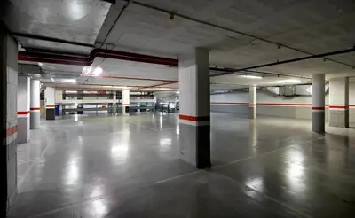 an empty parking garage with white columns and red stripes at HCC Montblanc in Barcelona