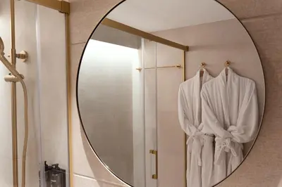 a mirror in a bathroom with a robe in it at Tres Torres Atiram Hotel in Barcelona