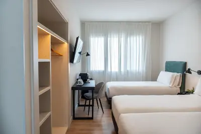 a hotel room with two beds and a desk at Tres Torres Atiram Hotel in Barcelona